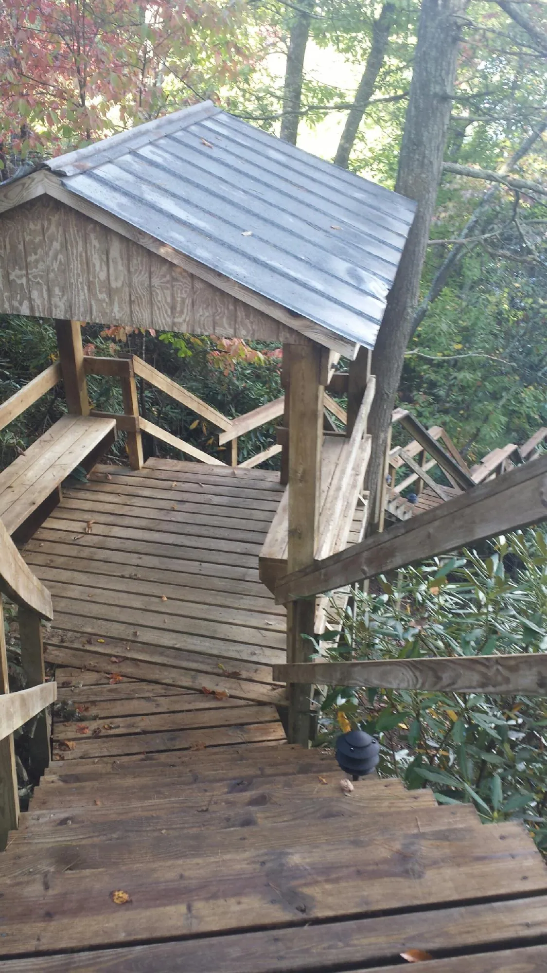 Metal roofed shelter over wooden steps on a wooded walkway — Skylight Repair & Installation work by our crew in Wellsville